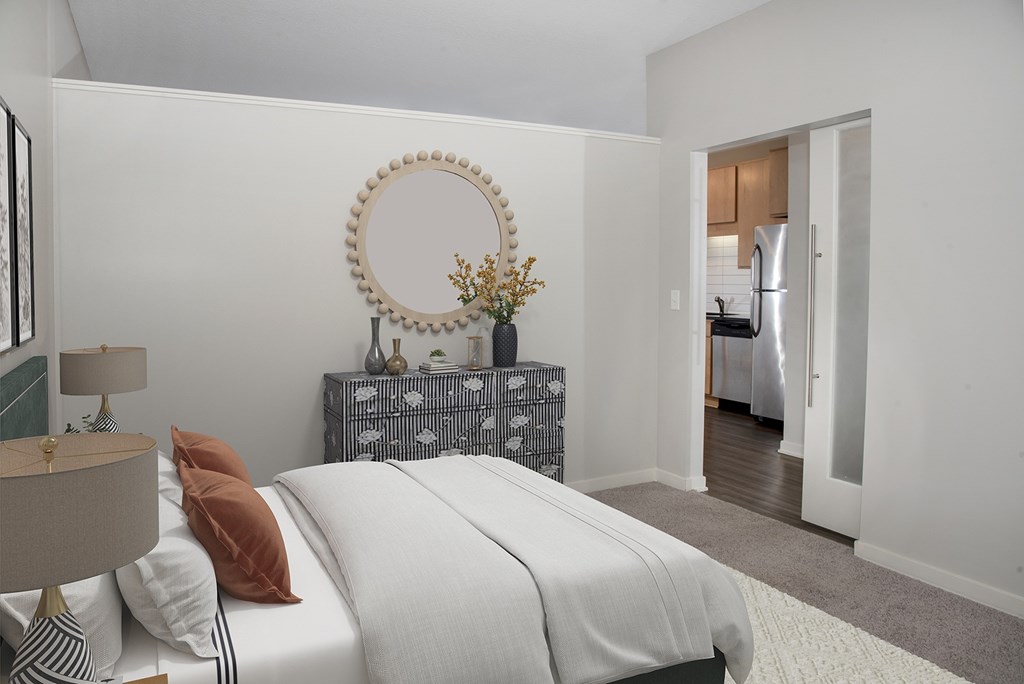 A bedroom with a bed, nightstand, and a mirror on the wall.