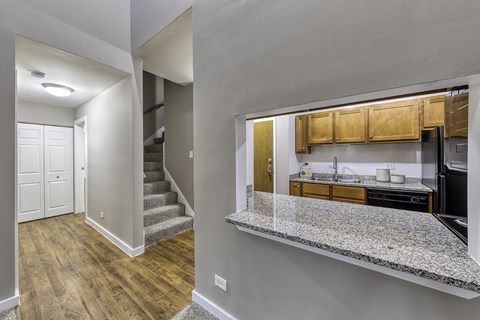 A kitchen with a counter top that overlooks the stairs.