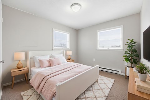 A bedroom with a bed, nightstands, and a plant.