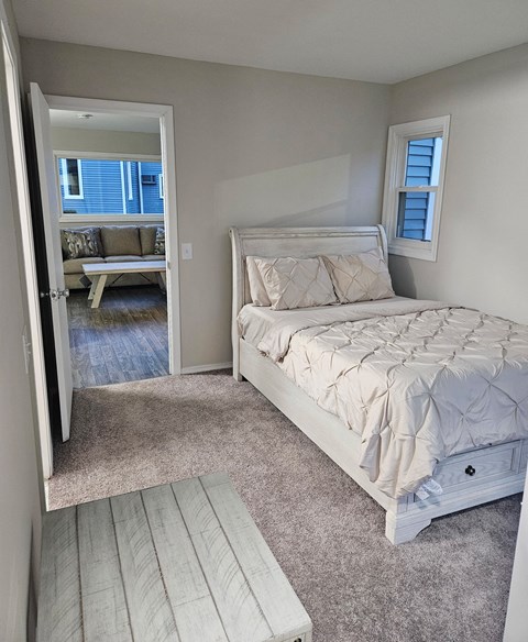 a bedroom with a bed and a door to a living room