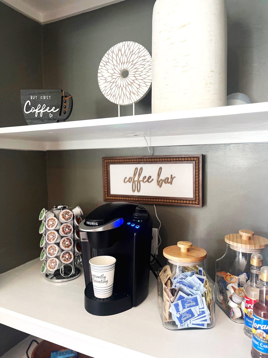 a coffee bar in a kitchen with a coffee maker and coffee cups on a shelf