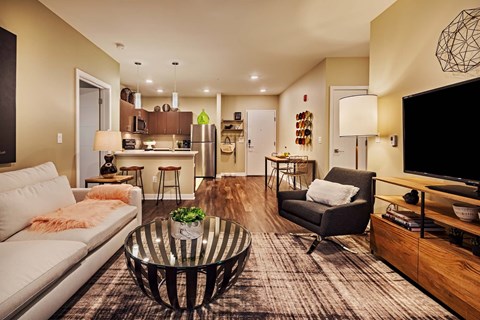 A modern living room with a glass coffee table and a grey sofa.