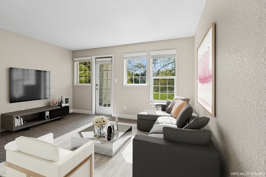 A living room with a grey couch, a white armchair, a coffee table, and a flat screen TV.