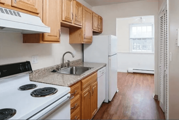 an empty kitchen with wood cabinets and white appliances