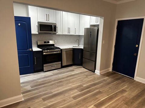 A kitchen with a blue door and a stove top oven.