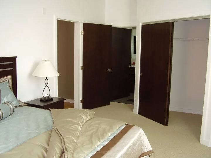 A bedroom with a bed, nightstand, and closet.