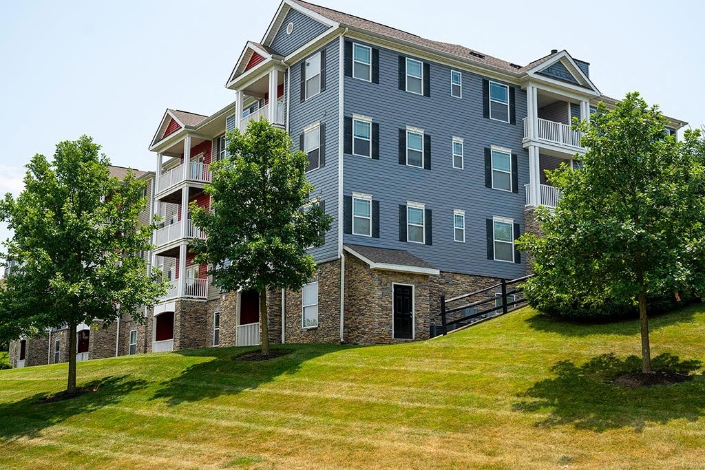 an apartment building on a grassy hill with trees in front of it  at ReNew Glenmoore, Glenmoore, PA