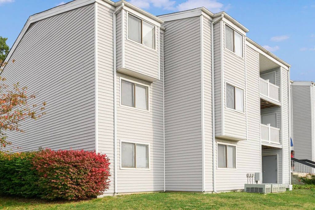 a white apartment building with a red shrub in front of it at ReNew Odenton, Maryland, 21113