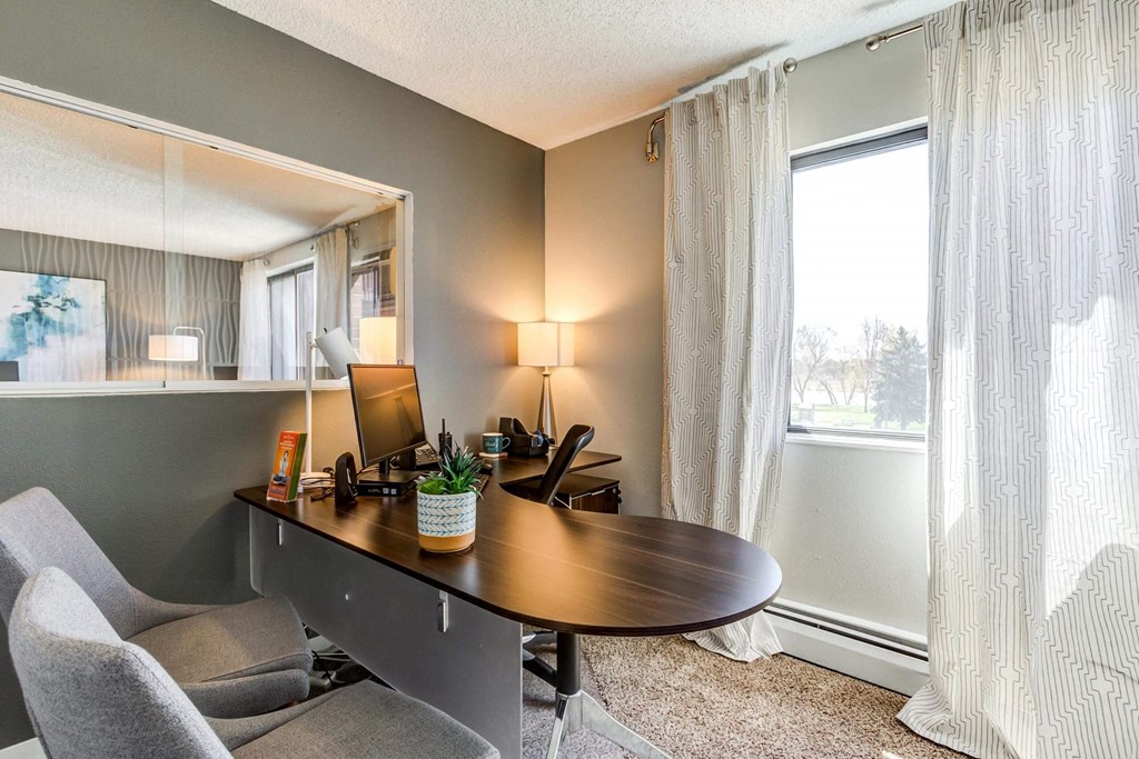 a desk with a computer and a chair in a room with a large window  at ReNew at Neill Lake, Eden Prairie