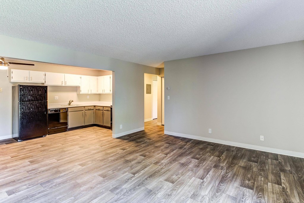 an empty living room with a kitchen in the background  at ReNew at Neill Lake, Eden Prairie