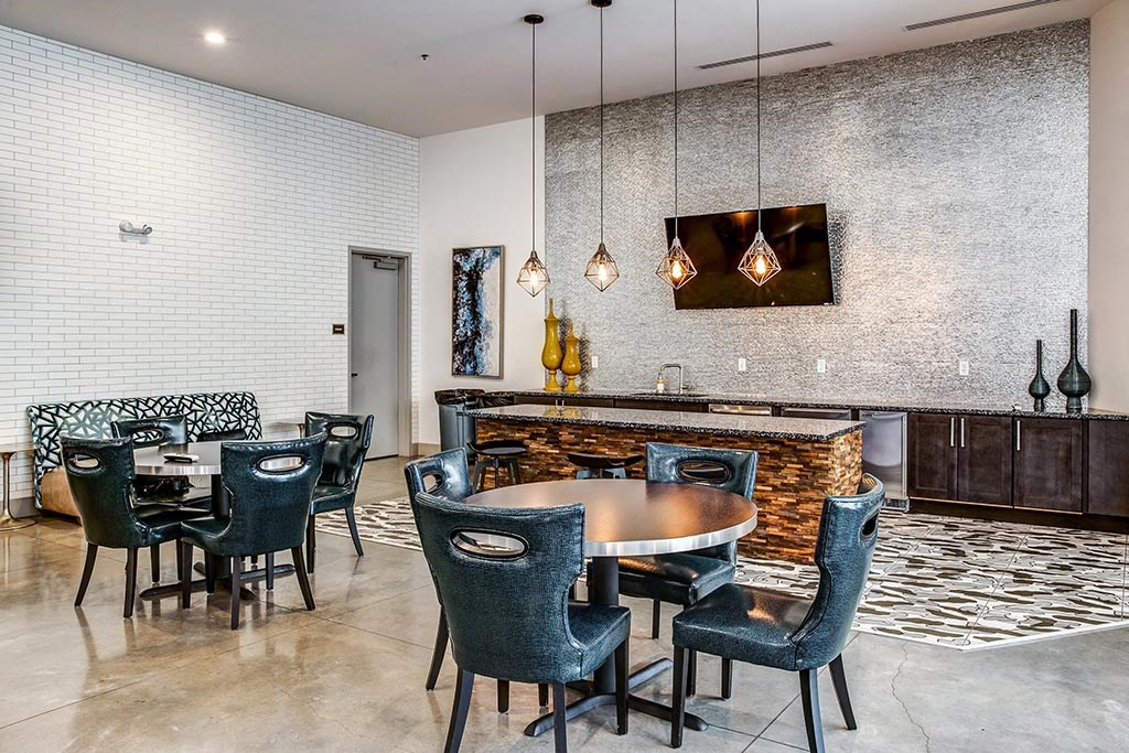 a dining area with a table and chairs and a bar in the background