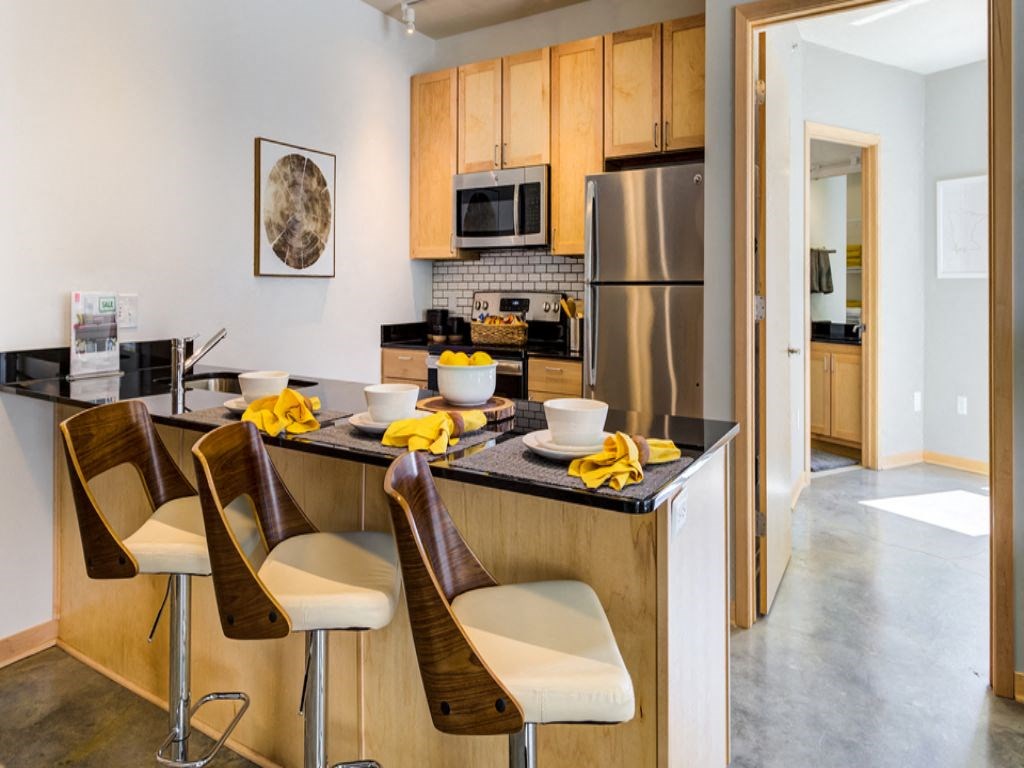 a kitchen with a bar and chairs and a stainless steel refrigerator