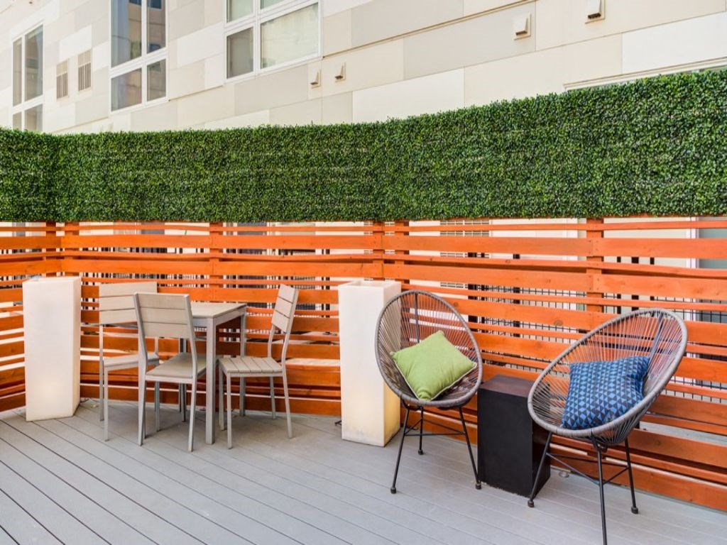 a patio with a table and chairs and a wall of wooden boards