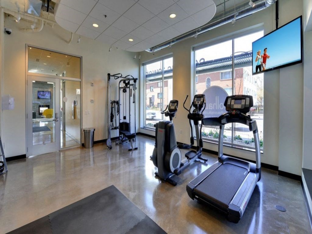 a gym with cardio equipment and windows in a building