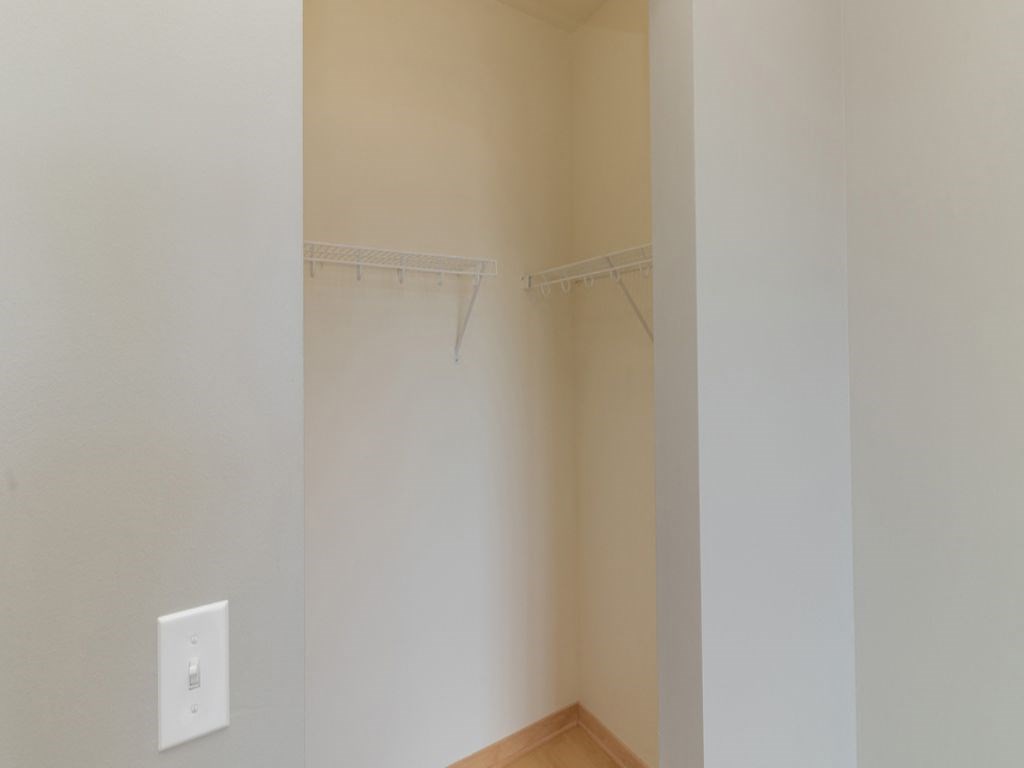 a walk in closet with a white wall and a shower curtain