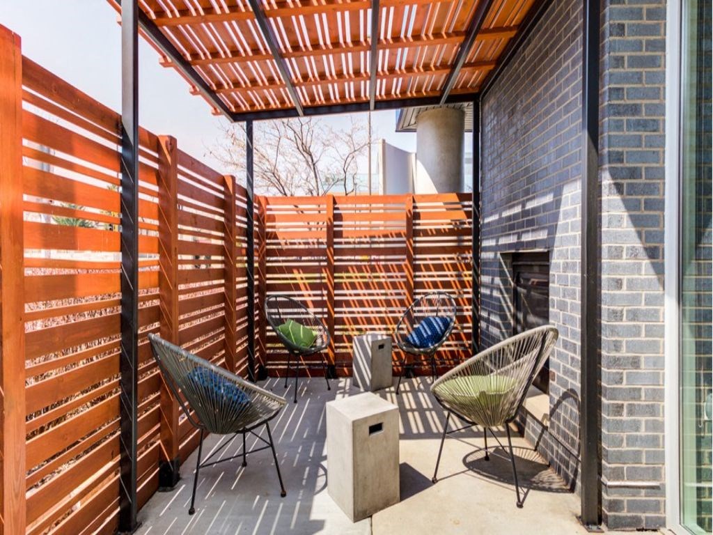 a covered patio with chairs and a fireplace