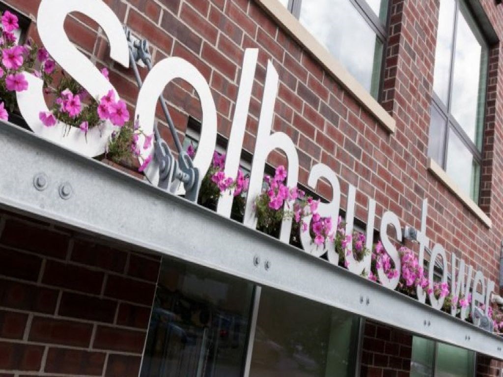 a sign on the side of a building with flowers on it