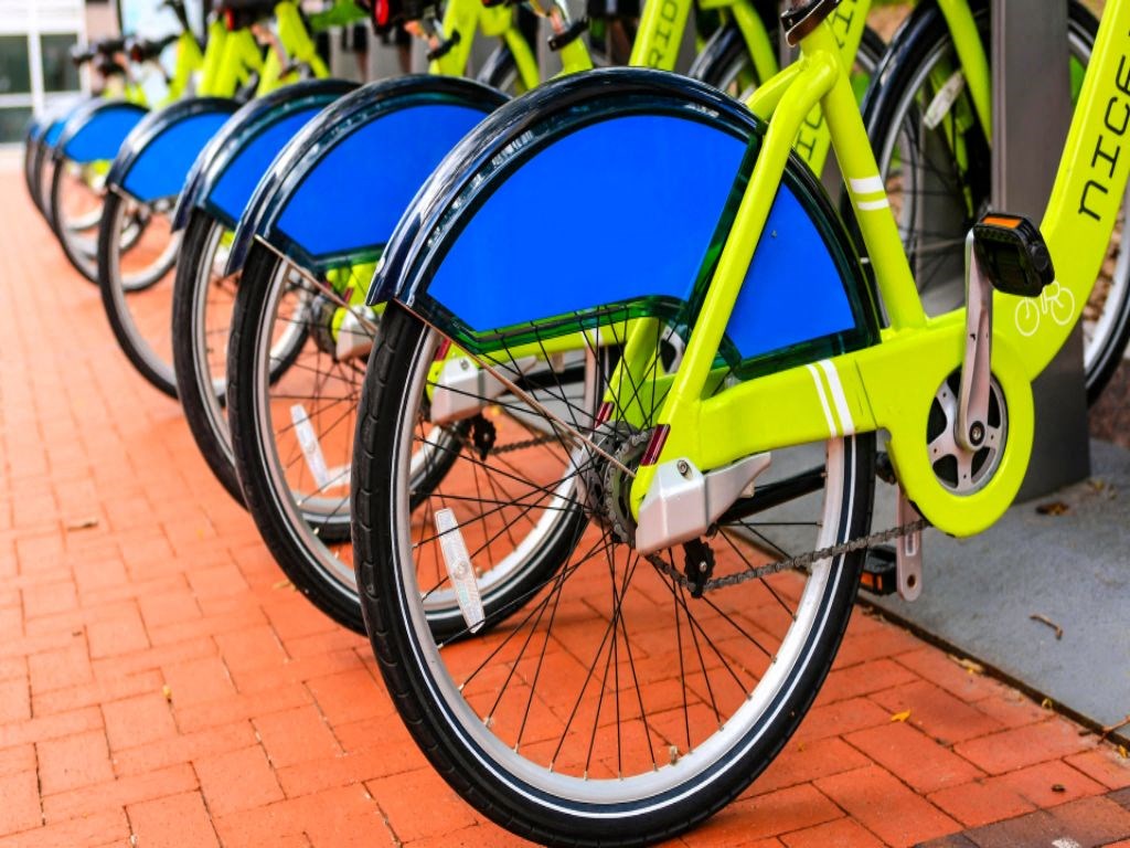 a row of yellow and blue bikes parked on a sidewalk