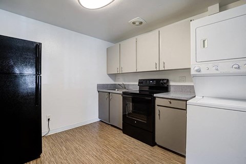 A kitchen with black fridge, white oven, and wooden floors.