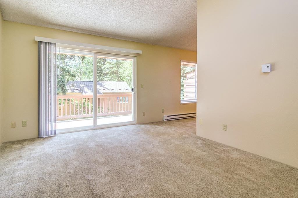 an empty living room with a sliding glass door and a balcony  at The Bluffs at Mountain Park, Oregon
