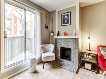 A living room with a fireplace, chair, and a window.