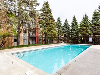 A swimming pool surrounded by trees and a building in the background.