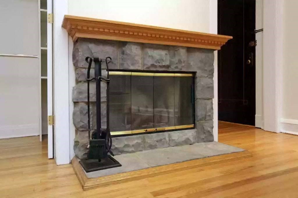 a stone fireplace in a living room with a wood floor at The Bryant at Oak Park I & II, Oak Park, IL 60302