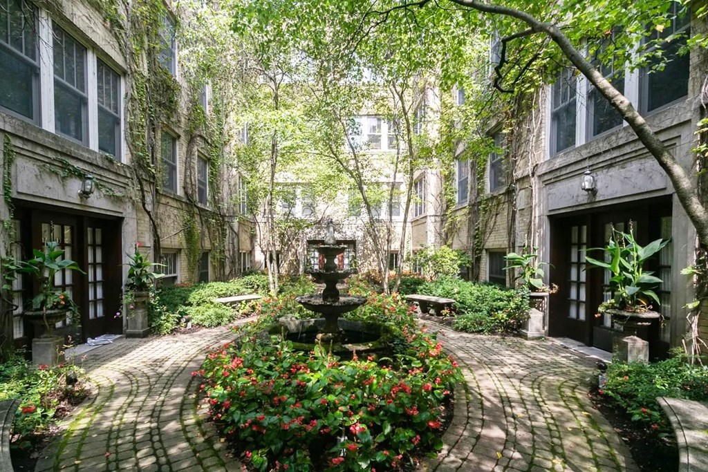 a courtyard with a fountain and flowers in front of a building at The Bryant at Oak Park I & II, Oak Park
