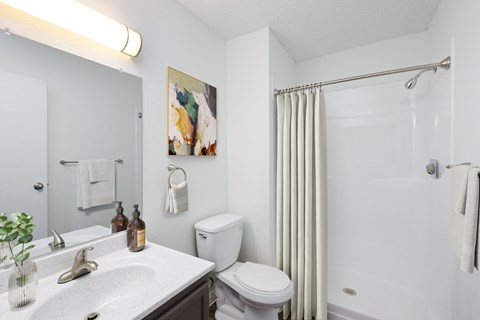 A white bathroom with a toilet, sink, and shower.