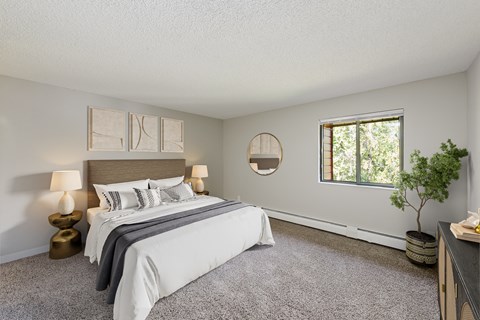 A bedroom with a large bed, two lamps, and a potted plant.