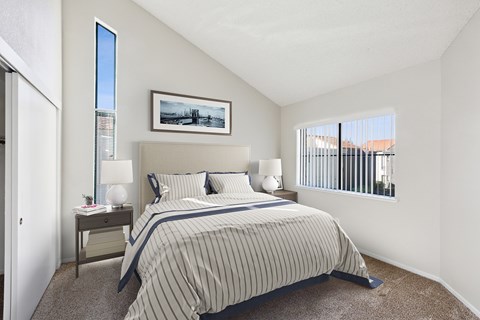 A bedroom with a bed, nightstand, and a painting on the wall.