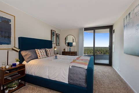 A bedroom with a large bed and a view of the balcony.