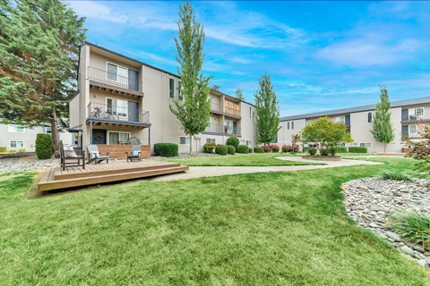 A sunny day at a well-kept apartment complex with a green lawn and trees. at River Lofts Apartments, Tualatin, Oregon