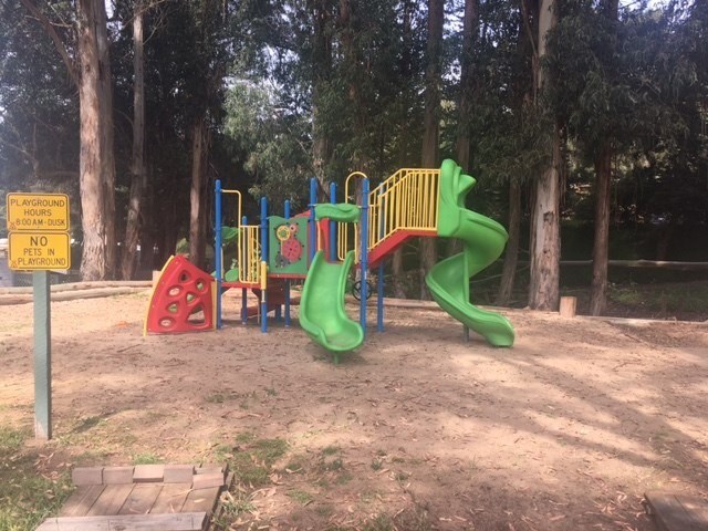 A playground with a green slide and a red and yellow structure at Salinas Sunset Apartments, Salinas, 93907