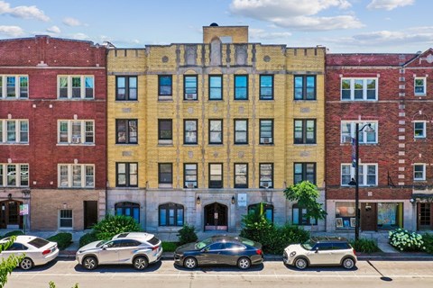 A row of buildings with cars parked in front.