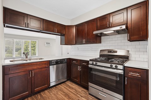 A kitchen with brown cabinets and a stainless steel oven.