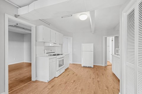 A kitchen with white cabinets and a wooden floor.