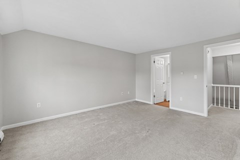 A spacious room with a carpeted floor and white walls.