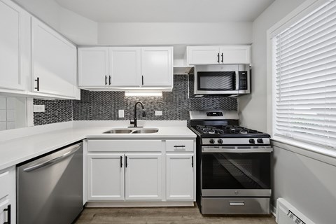 A kitchen with white cabinets and a black and white tiled backsplash.