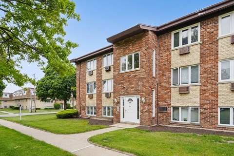 A brick apartment building with a white door and windows.