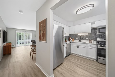 A modern kitchen with stainless steel appliances and wooden flooring.