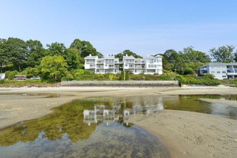 A beachfront property with a large white building and a green lawn.
