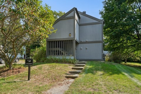 A laundry facility is located in a grassy area next to a building.