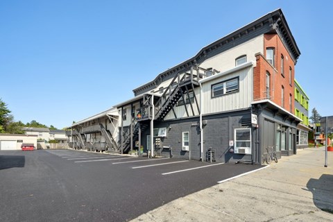 A parking lot with a building that has a staircase on its side.