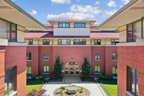 A red brick building with a circular entrance and a courtyard in front.