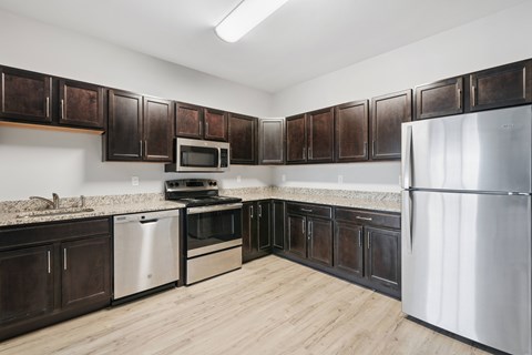 A kitchen with dark brown cabinets and stainless steel appliances.