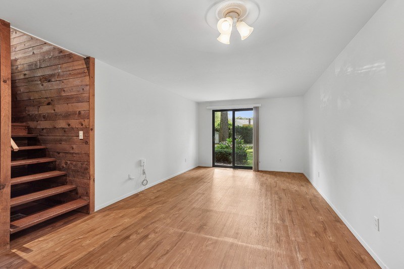 A room with wooden floors and a staircase on the left side.