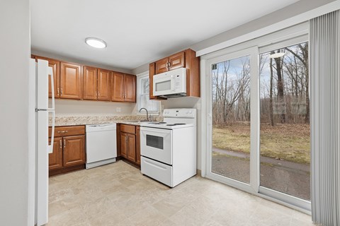 A kitchen with white appliances and wooden cabinets.