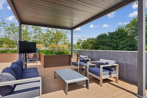 A patio with a grey sofa, blue cushions, and a wooden coffee table.