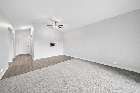 A spacious room with a carpeted floor and a ceiling fan.